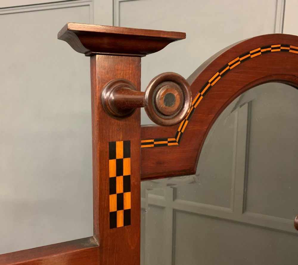An Arts and Crafts inlaid mahogany hall stand featuring an arched central mirror, coat pegs, marble surface, and integrated umbrella racks. View XVII