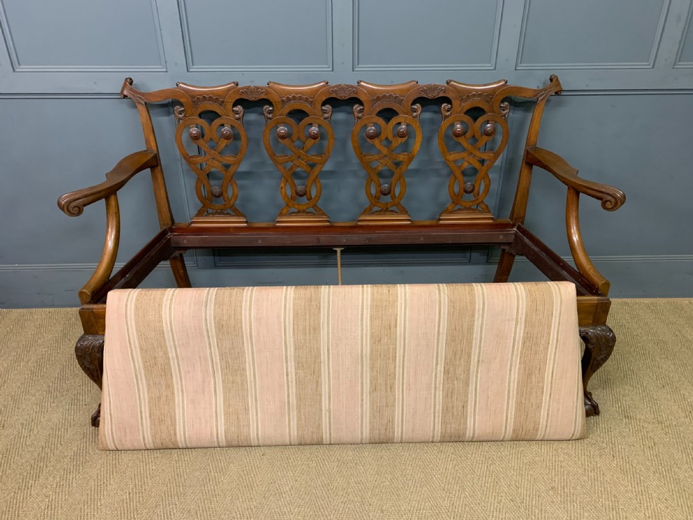 A carved mahogany Chippendale style settee featuring four pierced splats, scrolled arms, a striped fabric seat, and ball-and-claw feet. View III