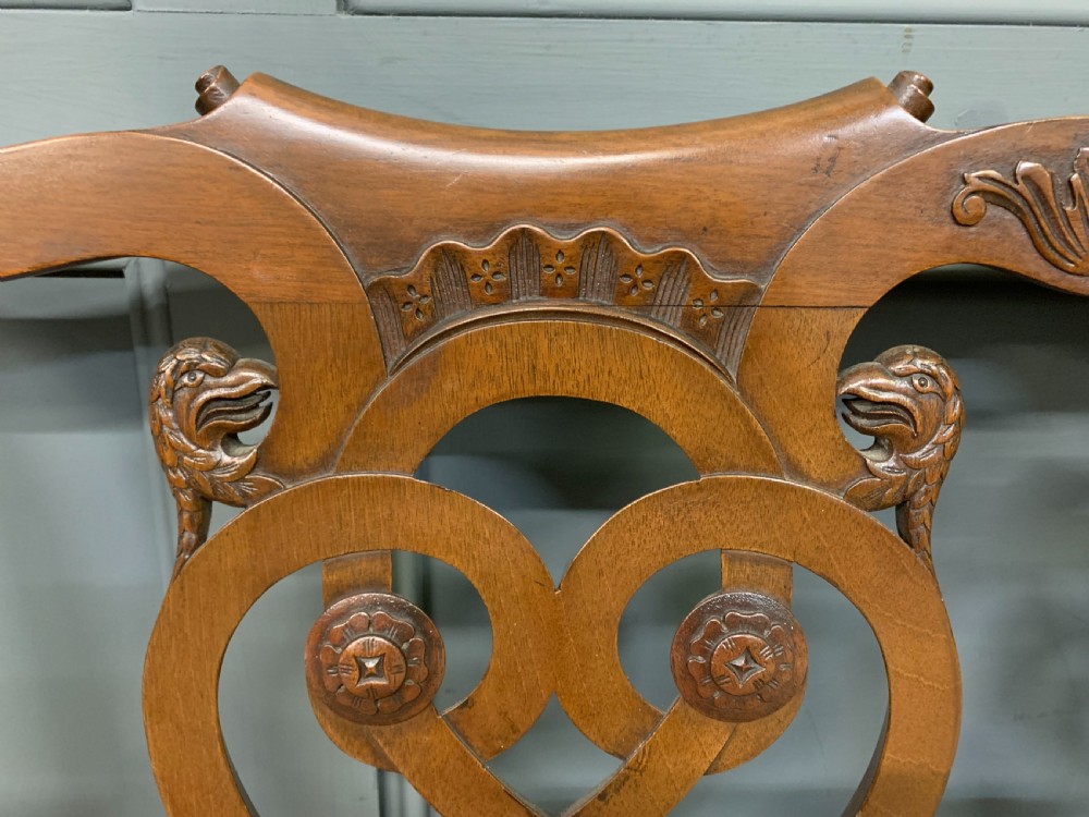 A carved mahogany Chippendale style settee featuring four pierced splats, scrolled arms, a striped fabric seat, and ball-and-claw feet. View VIII