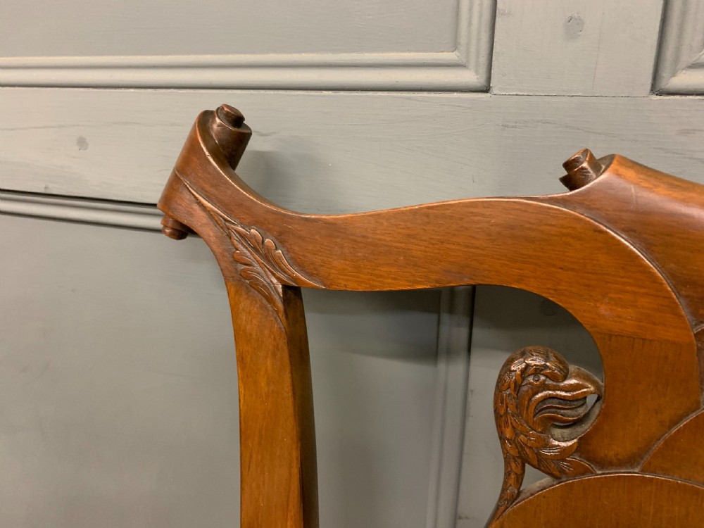 A carved mahogany Chippendale style settee featuring four pierced splats, scrolled arms, a striped fabric seat, and ball-and-claw feet. View IX