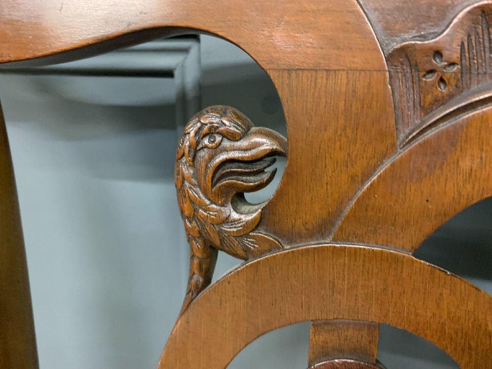 A carved mahogany Chippendale style settee featuring four pierced splats, scrolled arms, a striped fabric seat, and ball-and-claw feet. View XI