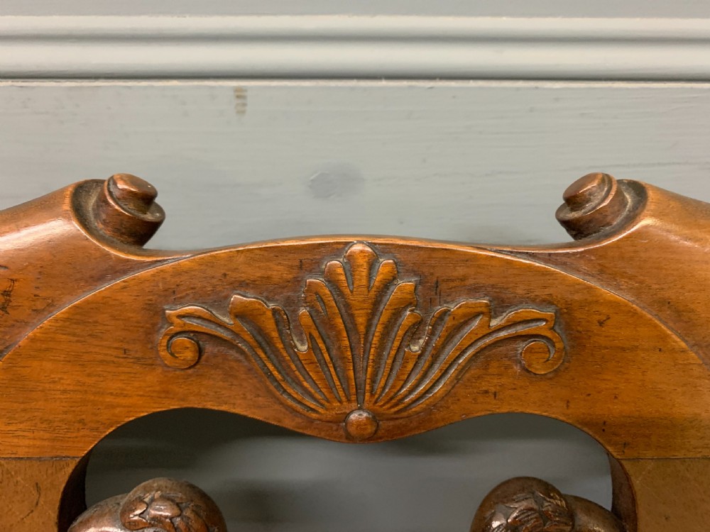 A carved mahogany Chippendale style settee featuring four pierced splats, scrolled arms, a striped fabric seat, and ball-and-claw feet. View XIII