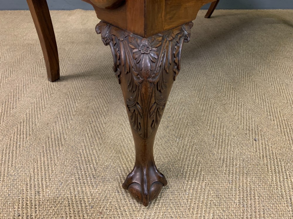 A carved mahogany Chippendale style settee featuring four pierced splats, scrolled arms, a striped fabric seat, and ball-and-claw feet. View XVIII