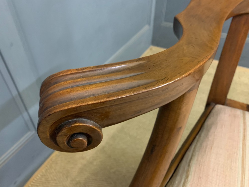 A carved mahogany Chippendale style settee featuring four pierced splats, scrolled arms, a striped fabric seat, and ball-and-claw feet. View XXII
