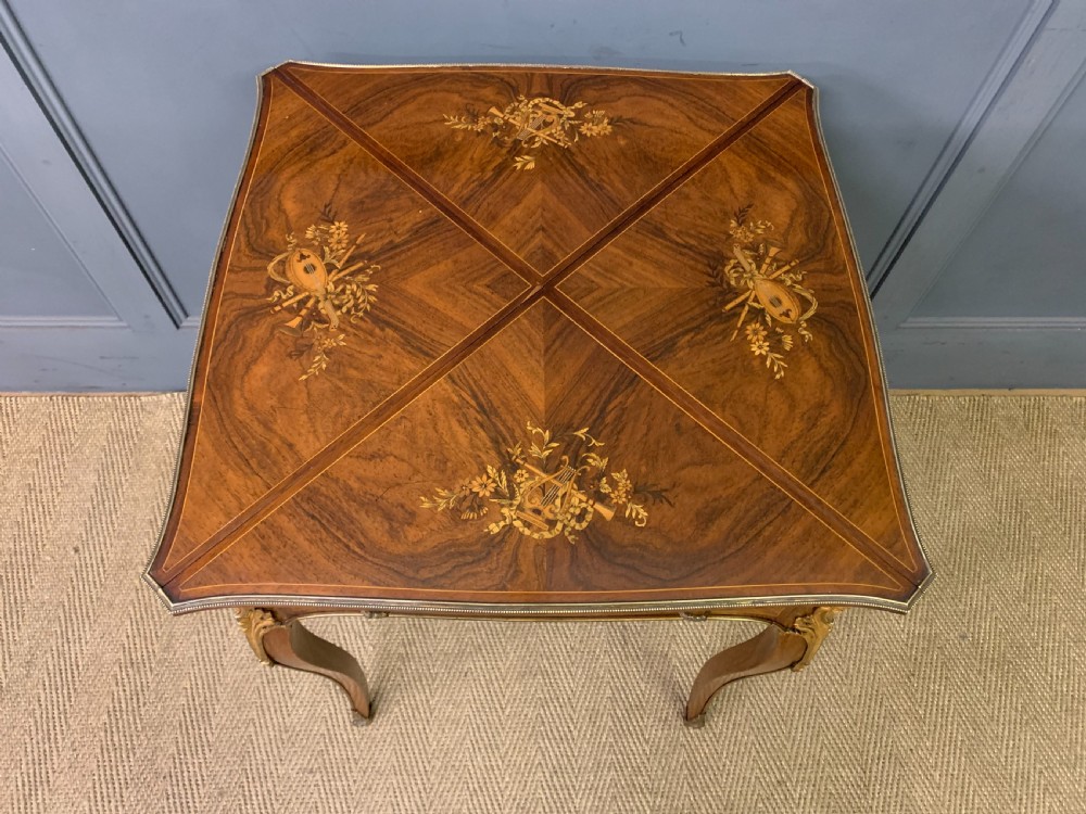 An Edwardian inlaid rosewood envelope card table featuring cabriole legs with brass mounts, a single drawer, and top flaps decorated with floral and musical instrument marquetry. View III