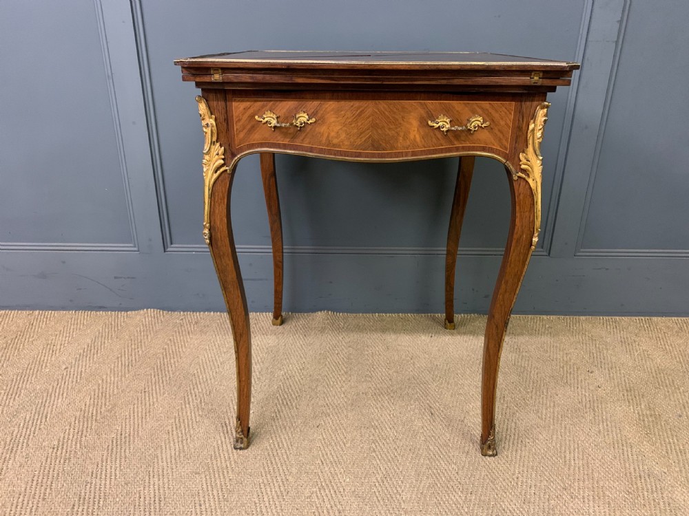 An Edwardian inlaid rosewood envelope card table featuring cabriole legs with brass mounts, a single drawer, and top flaps decorated with floral and musical instrument marquetry. View V