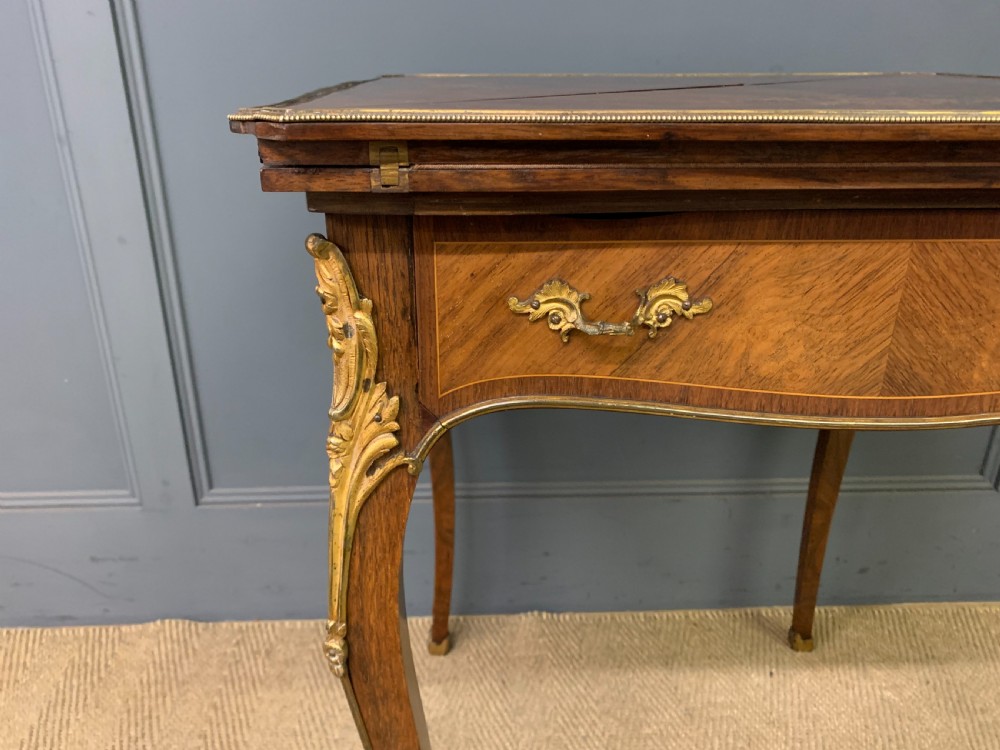 An Edwardian inlaid rosewood envelope card table featuring cabriole legs with brass mounts, a single drawer, and top flaps decorated with floral and musical instrument marquetry. View VIII