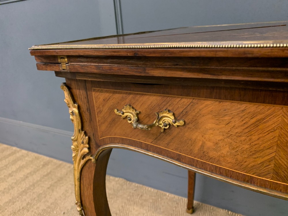An Edwardian inlaid rosewood envelope card table featuring cabriole legs with brass mounts, a single drawer, and top flaps decorated with floral and musical instrument marquetry. View IX
