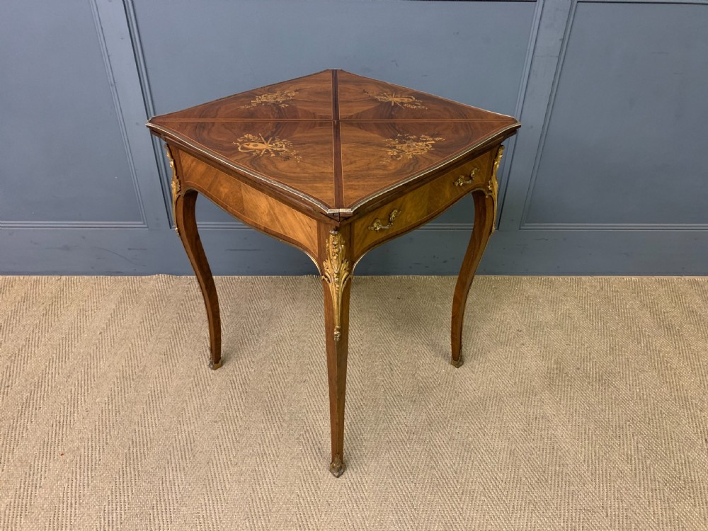An Edwardian inlaid rosewood envelope card table featuring cabriole legs with brass mounts, a single drawer, and top flaps decorated with floral and musical instrument marquetry. View XIV