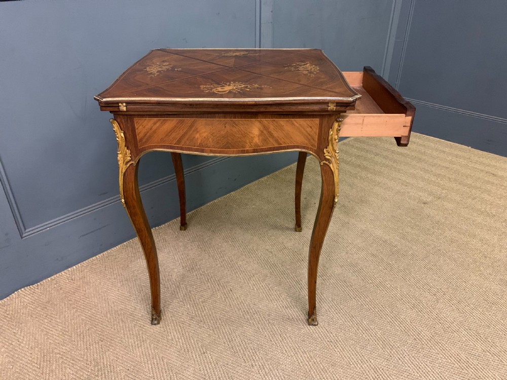 An Edwardian inlaid rosewood envelope card table featuring cabriole legs with brass mounts, a single drawer, and top flaps decorated with floral and musical instrument marquetry. View XV