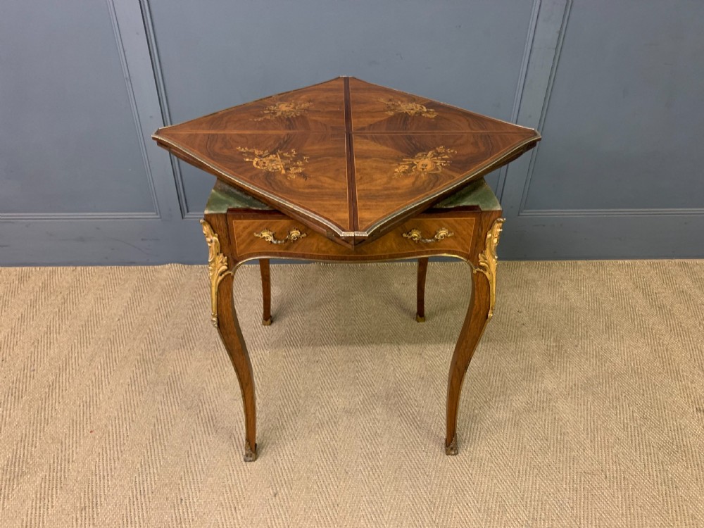 An Edwardian inlaid rosewood envelope card table featuring cabriole legs with brass mounts, a single drawer, and top flaps decorated with floral and musical instrument marquetry. View XIX