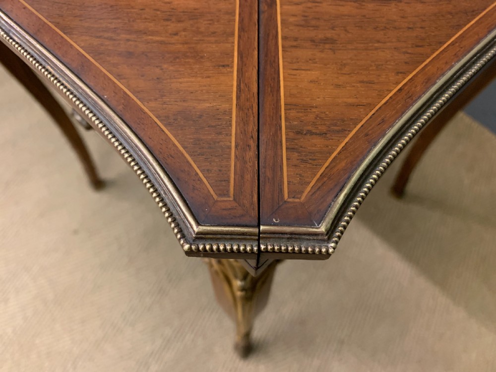 An Edwardian inlaid rosewood envelope card table featuring cabriole legs with brass mounts, a single drawer, and top flaps decorated with floral and musical instrument marquetry. View XX