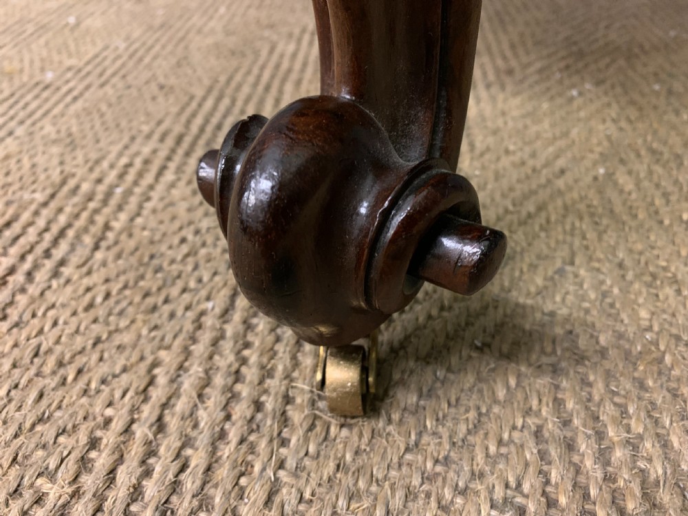 A Victorian rosewood high-back chair featuring intricately carved scrollwork, cream patterned damask upholstery, and cabriole front legs with brass castors. View XI