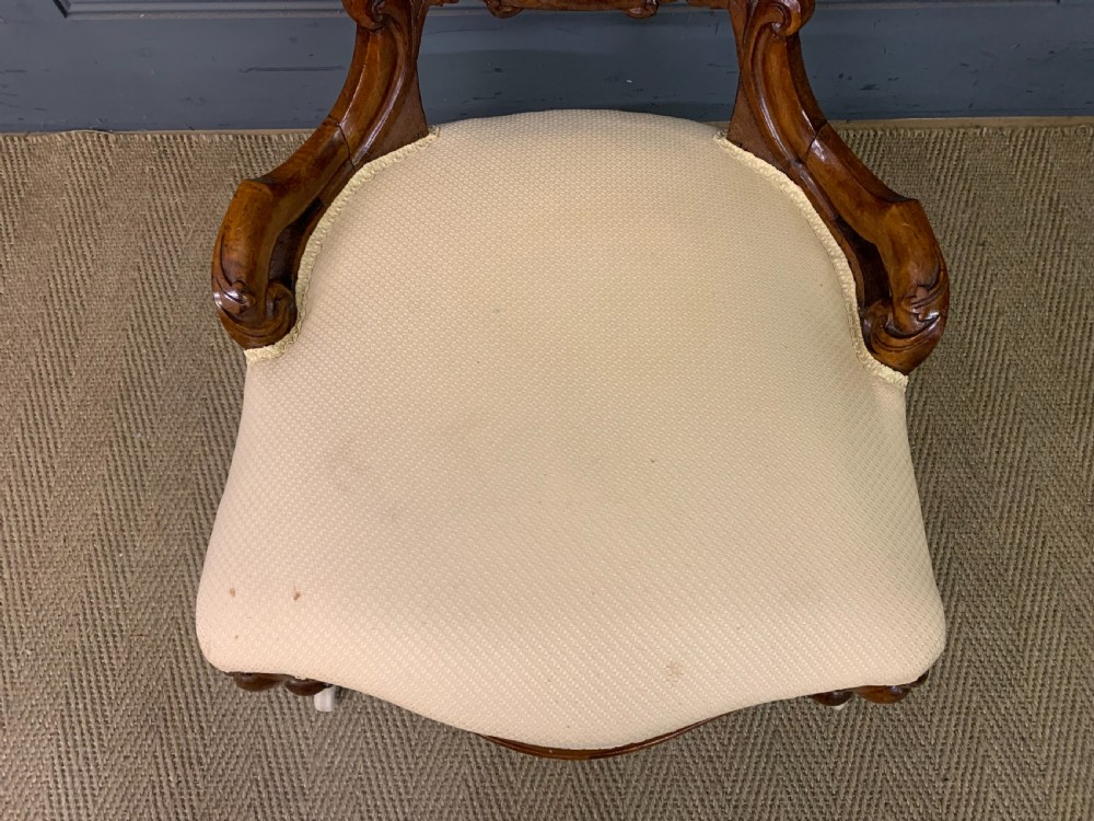 A Victorian walnut salon chair featuring a button-tufted cream backrest, carved wooden frame, cabriole front legs, and ceramic castors. View III