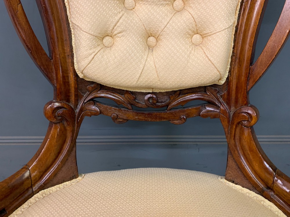 A Victorian walnut salon chair featuring a button-tufted cream backrest, carved wooden frame, cabriole front legs, and ceramic castors. View VII
