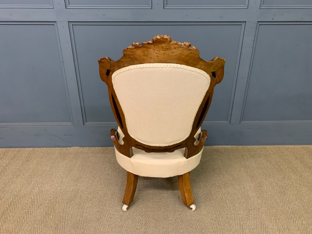 A Victorian walnut salon chair featuring a button-tufted cream backrest, carved wooden frame, cabriole front legs, and ceramic castors. View XIII