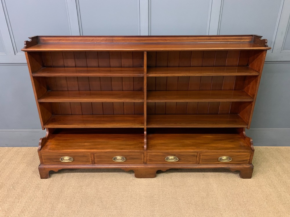 A wide Edwardian mahogany open bookcase with two multi-tiered shelving sections above four drawers with brass handles. View II