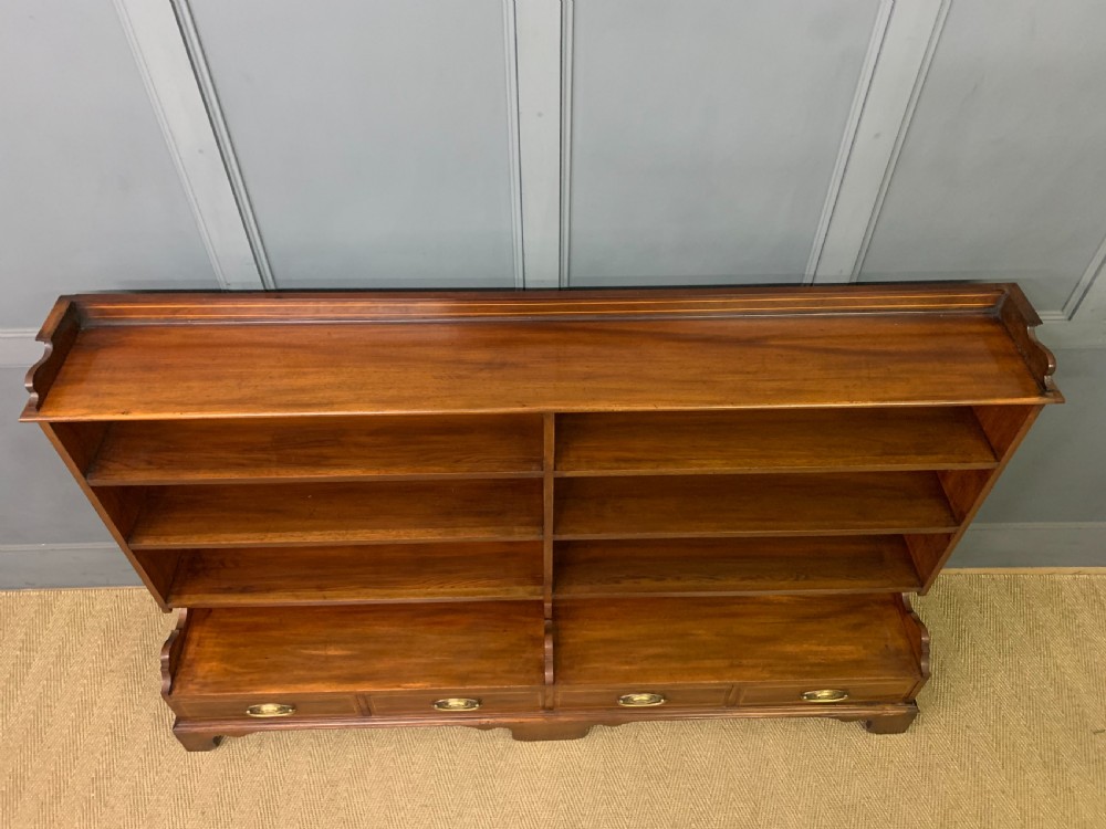 A wide Edwardian mahogany open bookcase with two multi-tiered shelving sections above four drawers with brass handles. View III