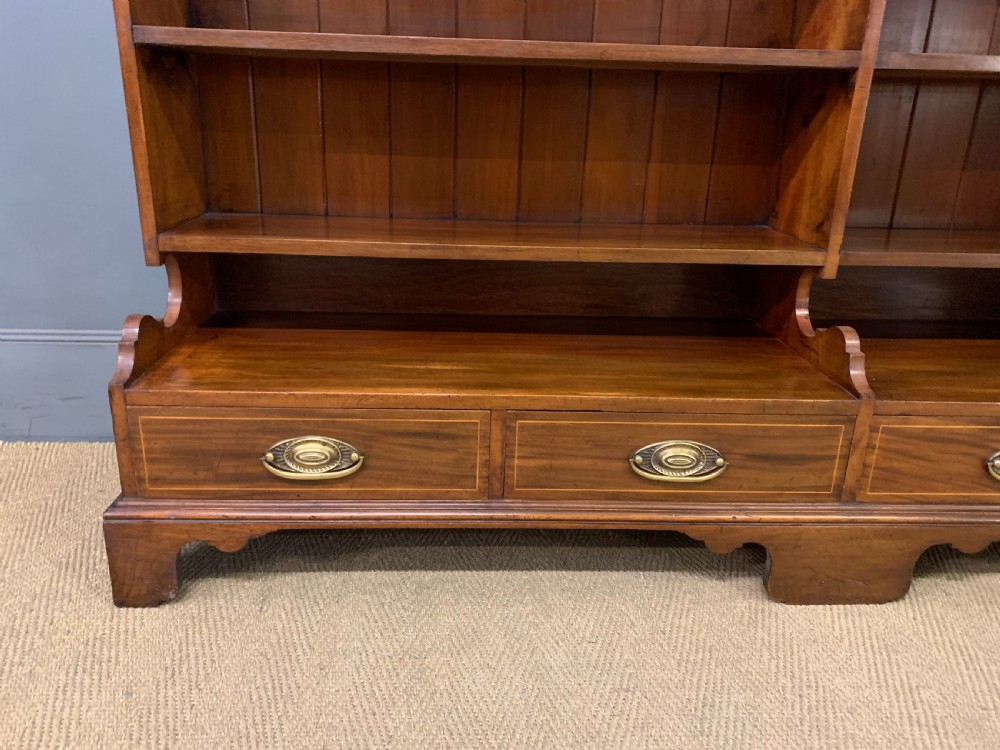 A wide Edwardian mahogany open bookcase with two multi-tiered shelving sections above four drawers with brass handles. View IV