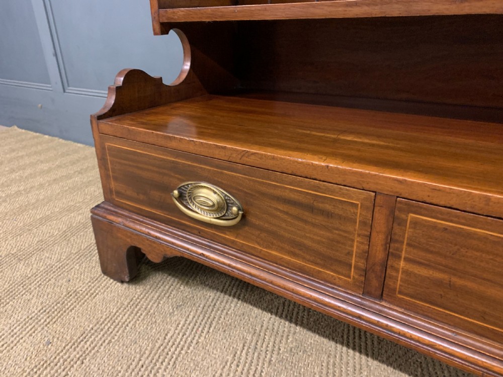 A wide Edwardian mahogany open bookcase with two multi-tiered shelving sections above four drawers with brass handles. View V