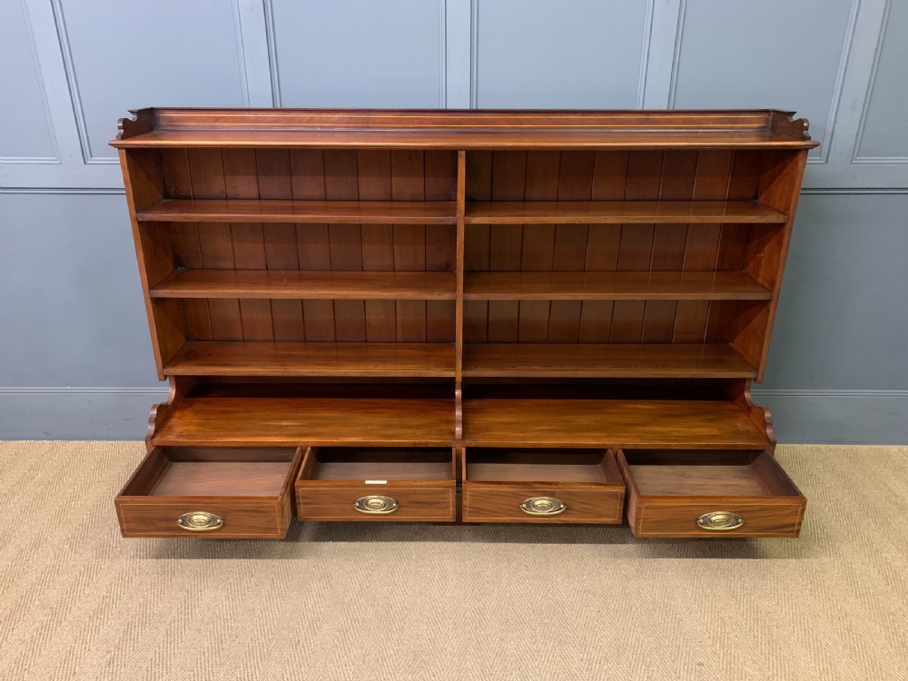 A wide Edwardian mahogany open bookcase with two multi-tiered shelving sections above four drawers with brass handles. View VII