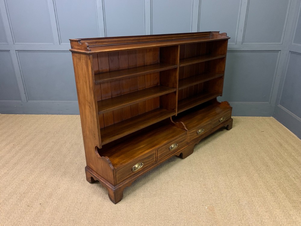 A wide Edwardian mahogany open bookcase with two multi-tiered shelving sections above four drawers with brass handles. View VIII