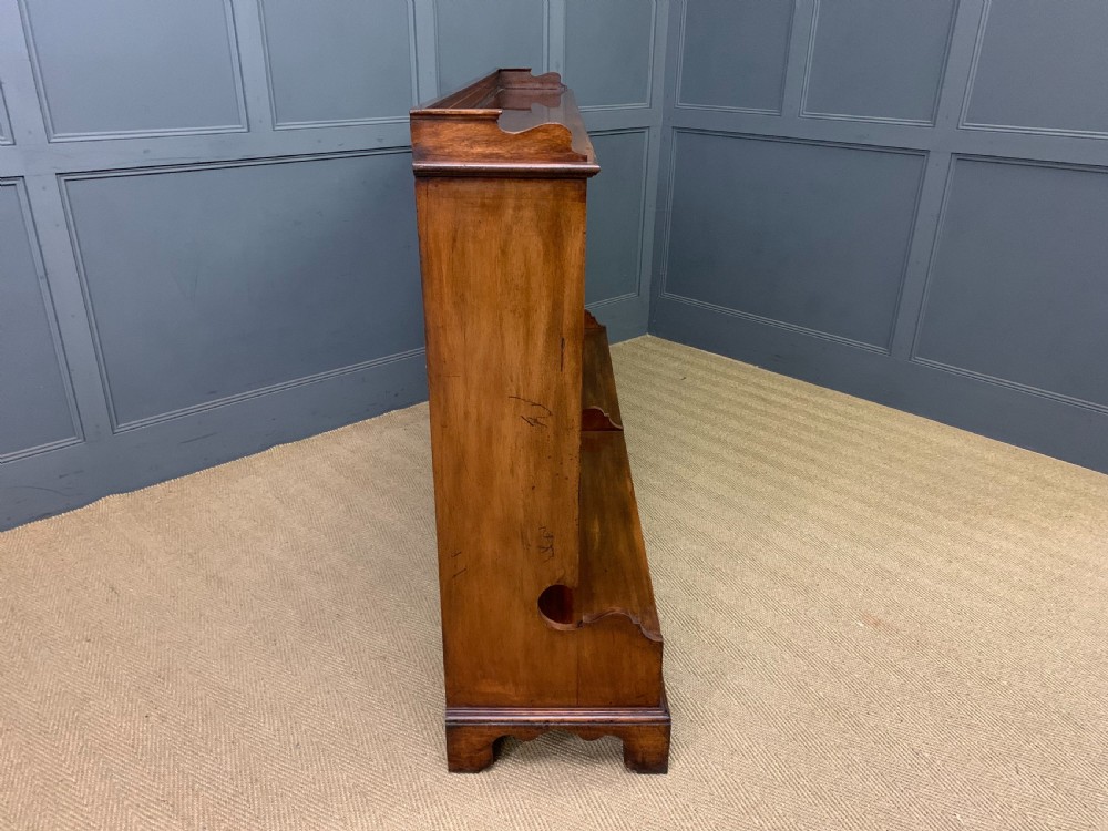 A wide Edwardian mahogany open bookcase with two multi-tiered shelving sections above four drawers with brass handles. View IX