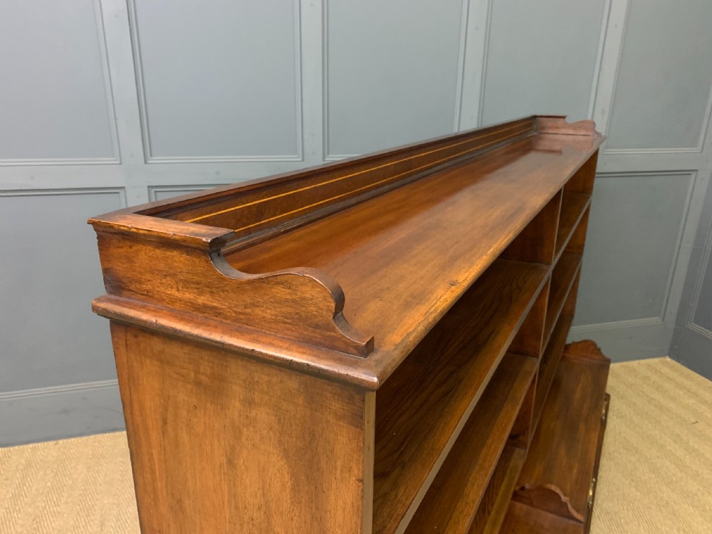 A wide Edwardian mahogany open bookcase with two multi-tiered shelving sections above four drawers with brass handles. View X