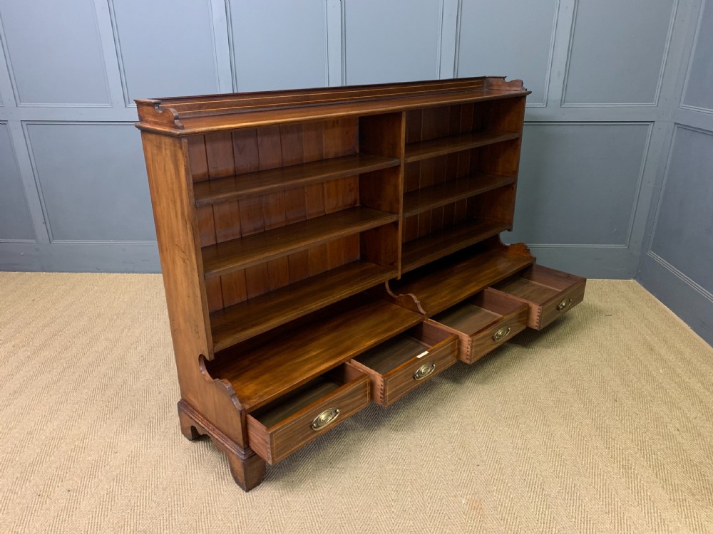A wide Edwardian mahogany open bookcase with two multi-tiered shelving sections above four drawers with brass handles. View XI