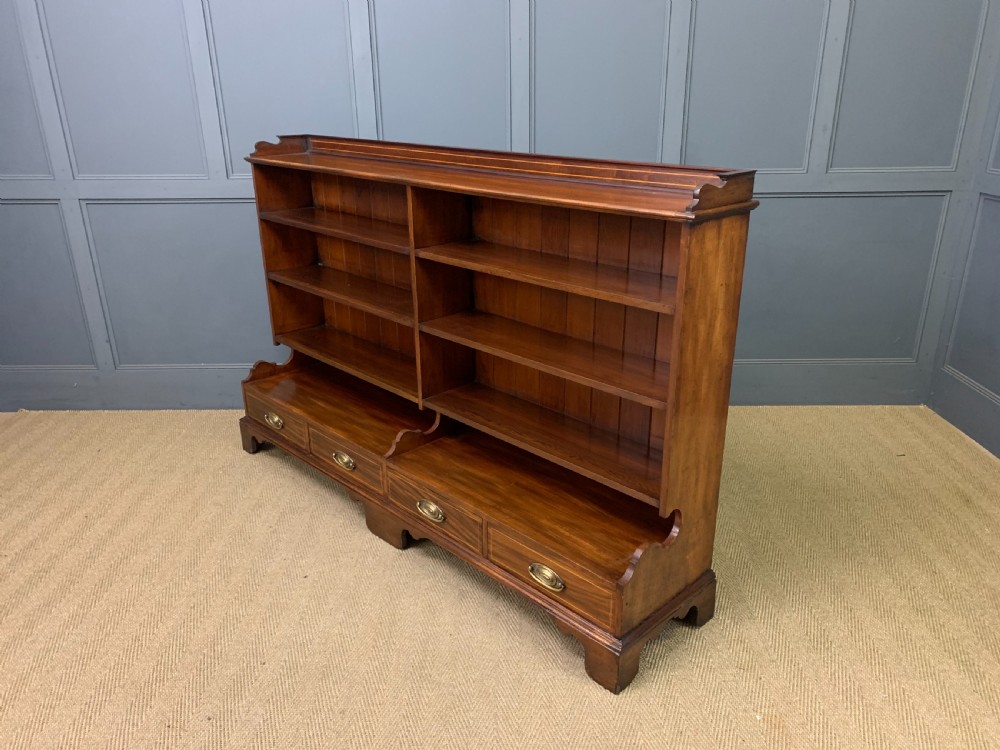 A wide Edwardian mahogany open bookcase with two multi-tiered shelving sections above four drawers with brass handles. View XII