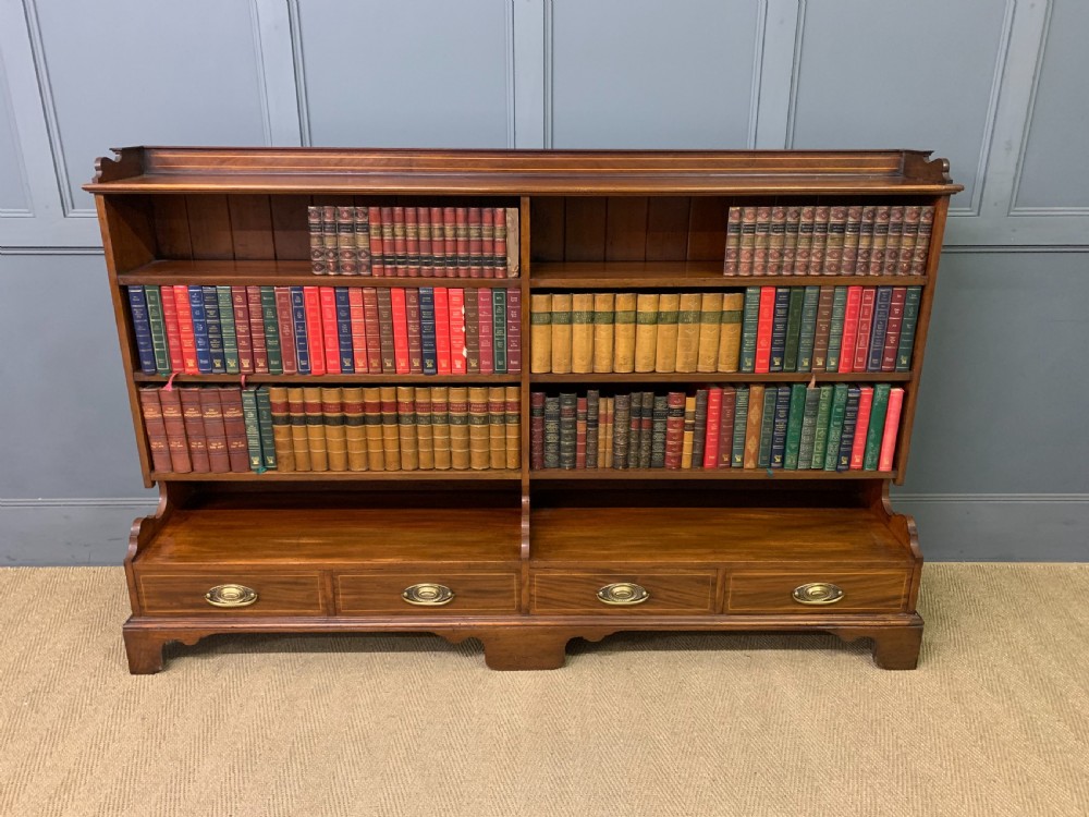 A wide Edwardian mahogany open bookcase with two multi-tiered shelving sections above four drawers with brass handles. View XIII