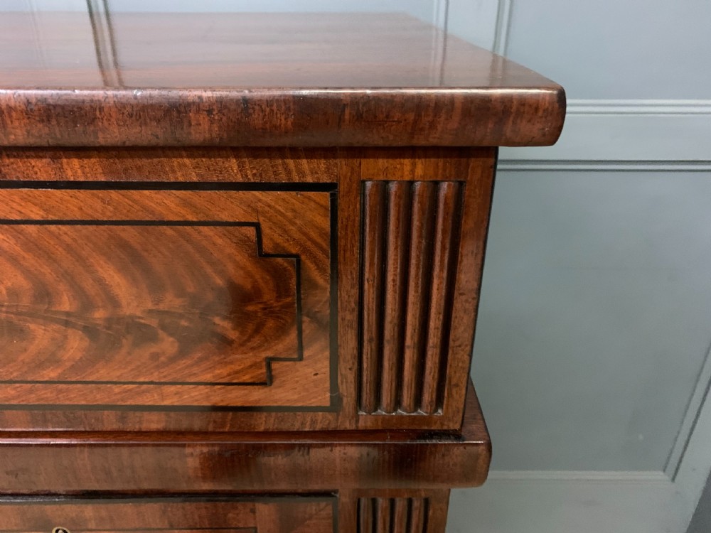 A Regency period flame mahogany sideboard featuring a raised stage top, central drawer, two side cupboards, detailed stringing, and turned reeded legs. View XIX