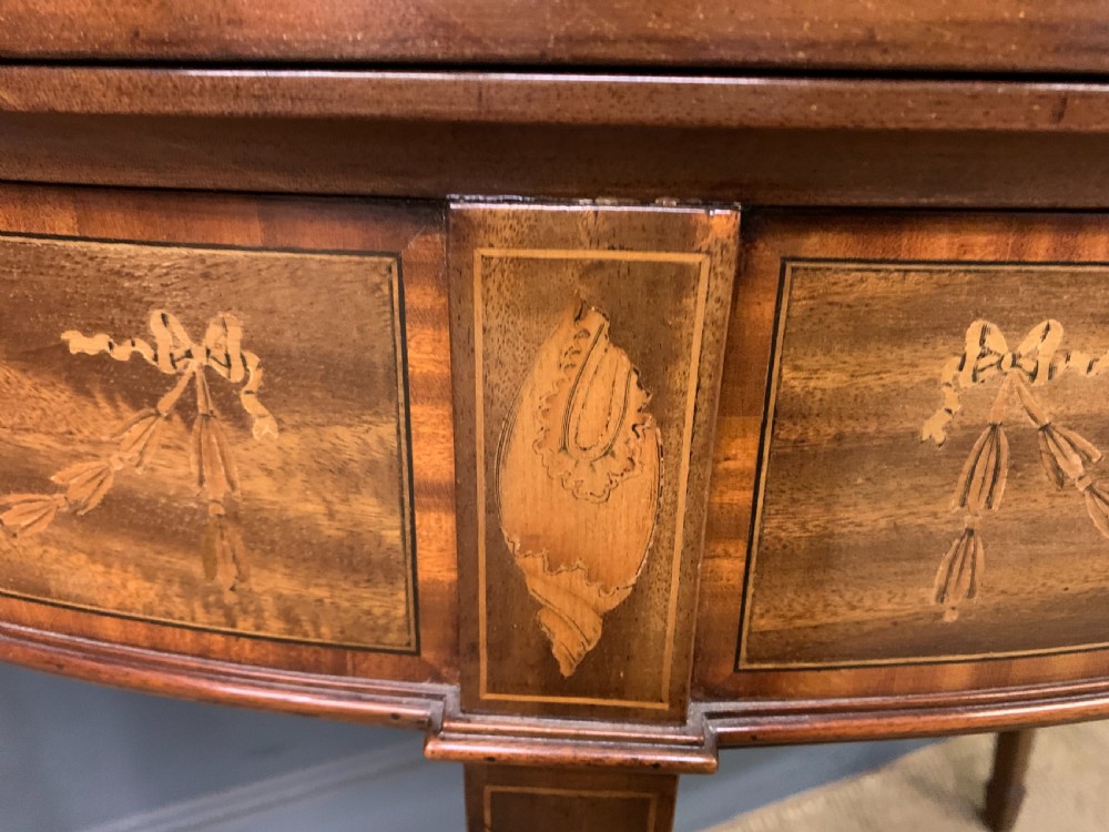 A demilune mahogany card table with floral marquetry inlays on the fold-over top and four square tapered legs. View X