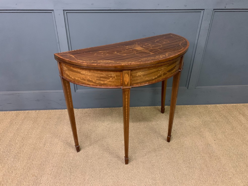 A demilune mahogany card table with floral marquetry inlays on the fold-over top and four square tapered legs. View XIII