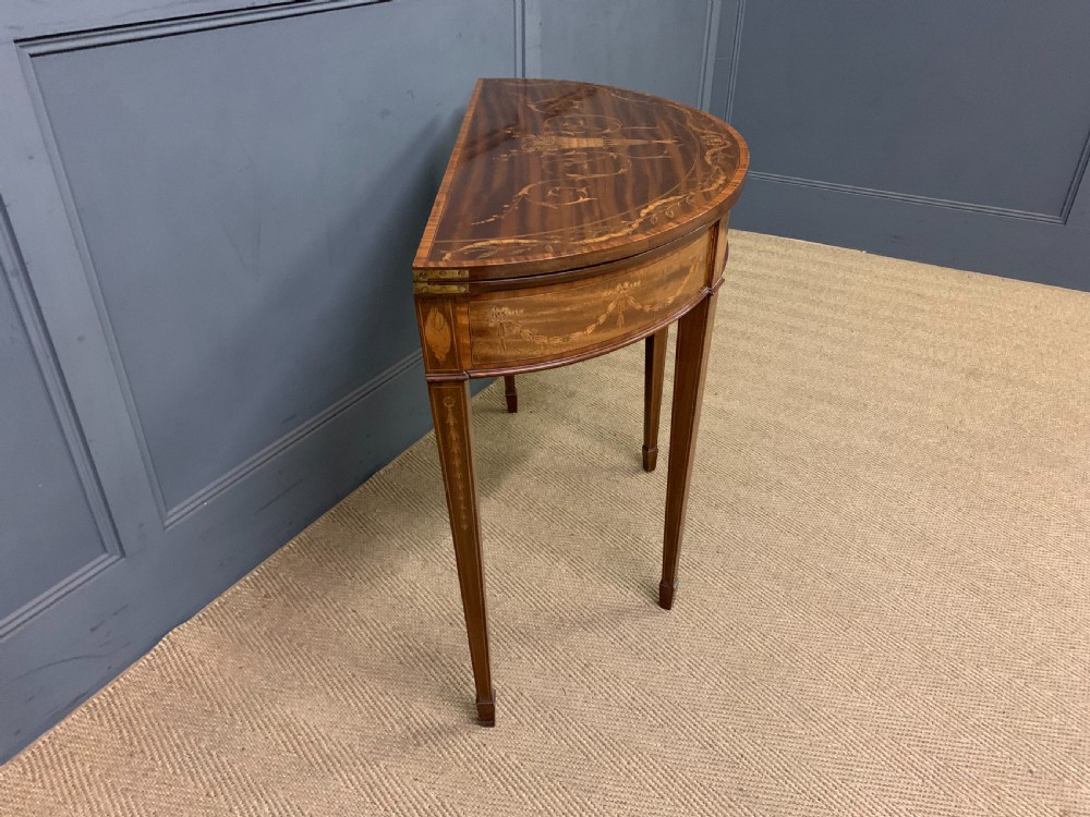A demilune mahogany card table with floral marquetry inlays on the fold-over top and four square tapered legs. View XIV