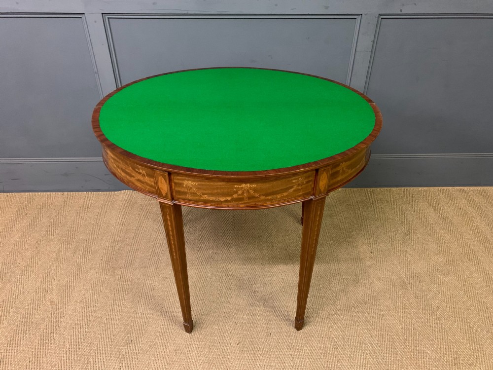 A demilune mahogany card table with floral marquetry inlays on the fold-over top and four square tapered legs. View XVIII