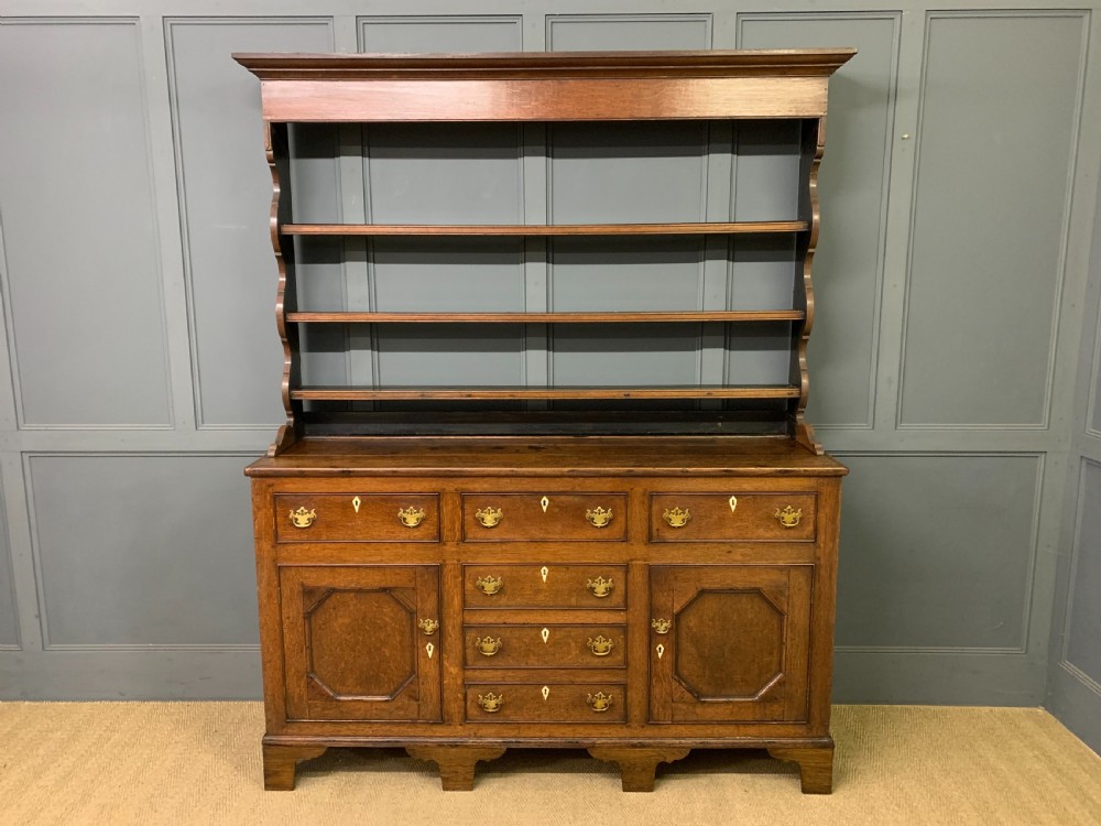 An early nineteenth-century Welsh oak dresser featuring a three-tier open plate rack above a base with drawers, cupboards, and brass hardware. View III