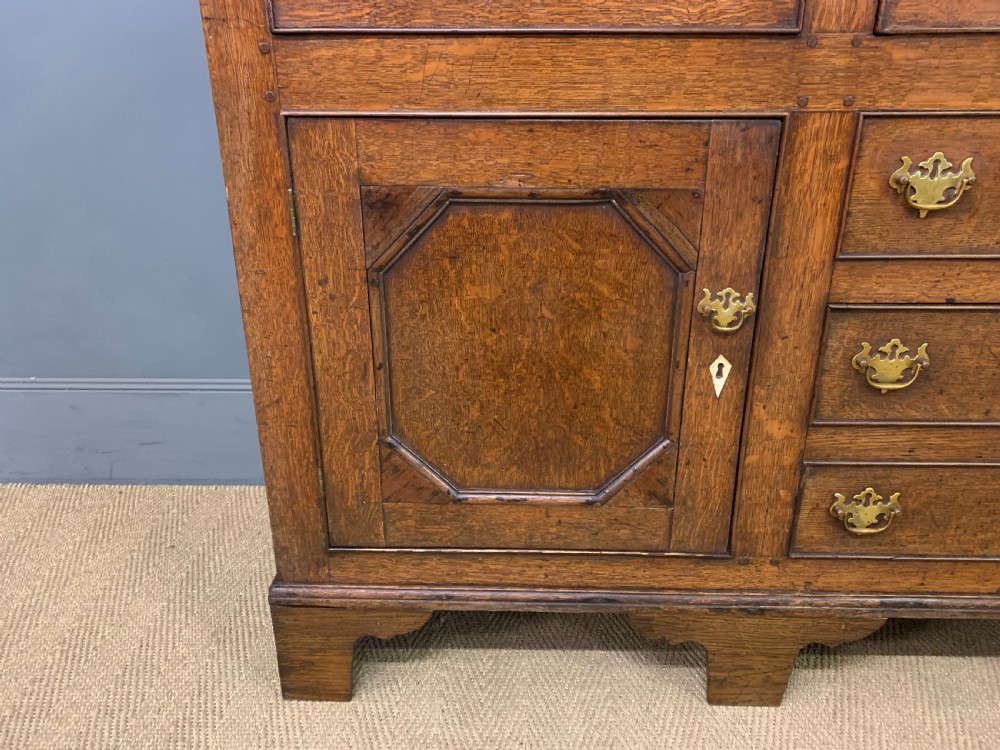 An early nineteenth-century Welsh oak dresser featuring a three-tier open plate rack above a base with drawers, cupboards, and brass hardware. View VIII
