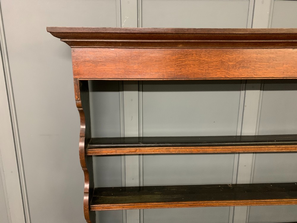 An early nineteenth-century Welsh oak dresser featuring a three-tier open plate rack above a base with drawers, cupboards, and brass hardware. View XIII