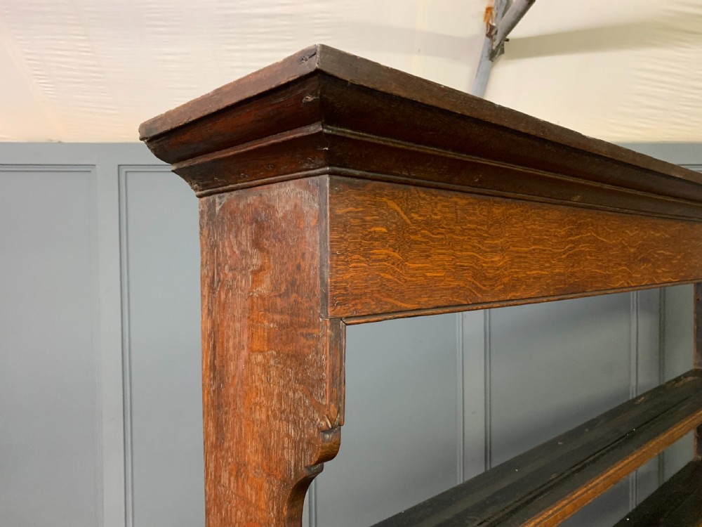 An early nineteenth-century Welsh oak dresser featuring a three-tier open plate rack above a base with drawers, cupboards, and brass hardware. View XVII