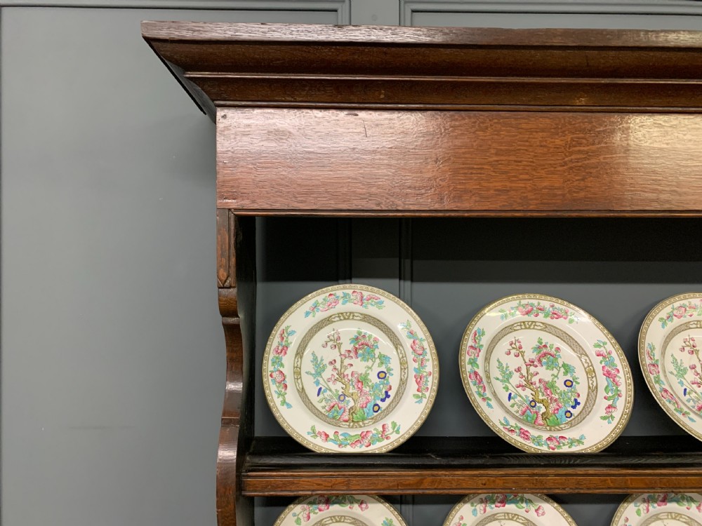 An early nineteenth-century Welsh oak dresser featuring a three-tier open plate rack above a base with drawers, cupboards, and brass hardware. View XX