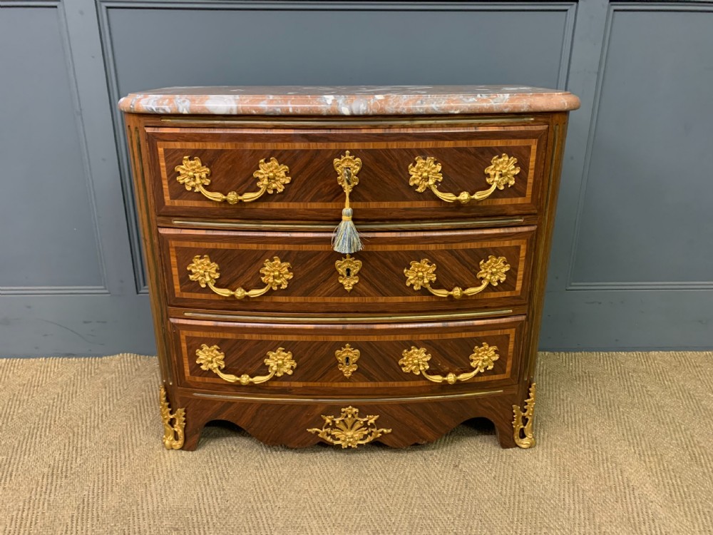 A French Louis XV style kingwood commode featuring three drawers, gilded metal mounts, and a variegated pink marble top. View II
