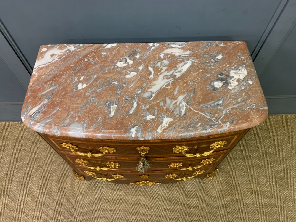A French Louis XV style kingwood commode featuring three drawers, gilded metal mounts, and a variegated pink marble top. View III
