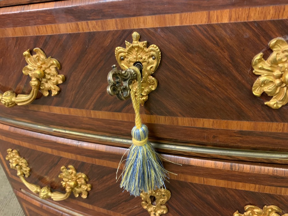 A French Louis XV style kingwood commode featuring three drawers, gilded metal mounts, and a variegated pink marble top. View VI
