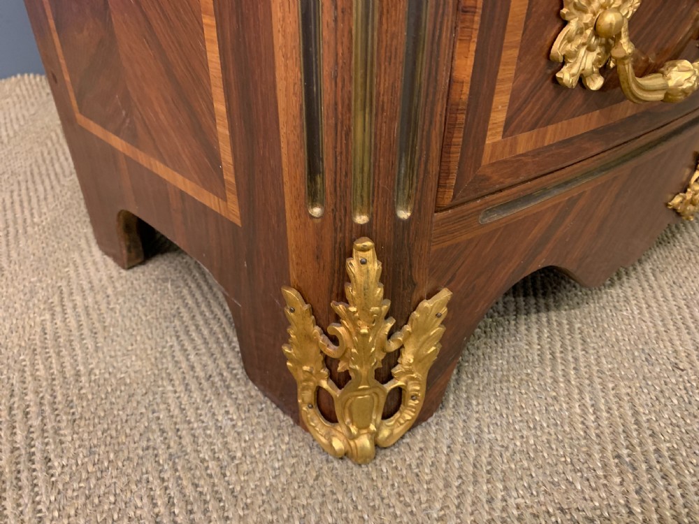A French Louis XV style kingwood commode featuring three drawers, gilded metal mounts, and a variegated pink marble top. View IX