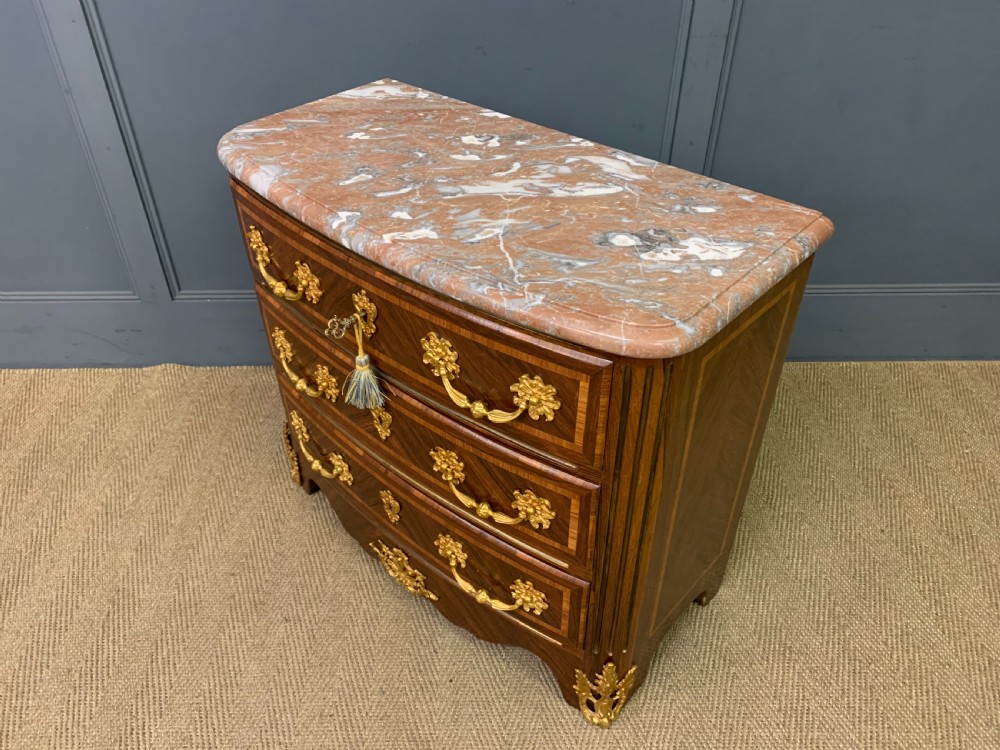 A French Louis XV style kingwood commode featuring three drawers, gilded metal mounts, and a variegated pink marble top. View XII