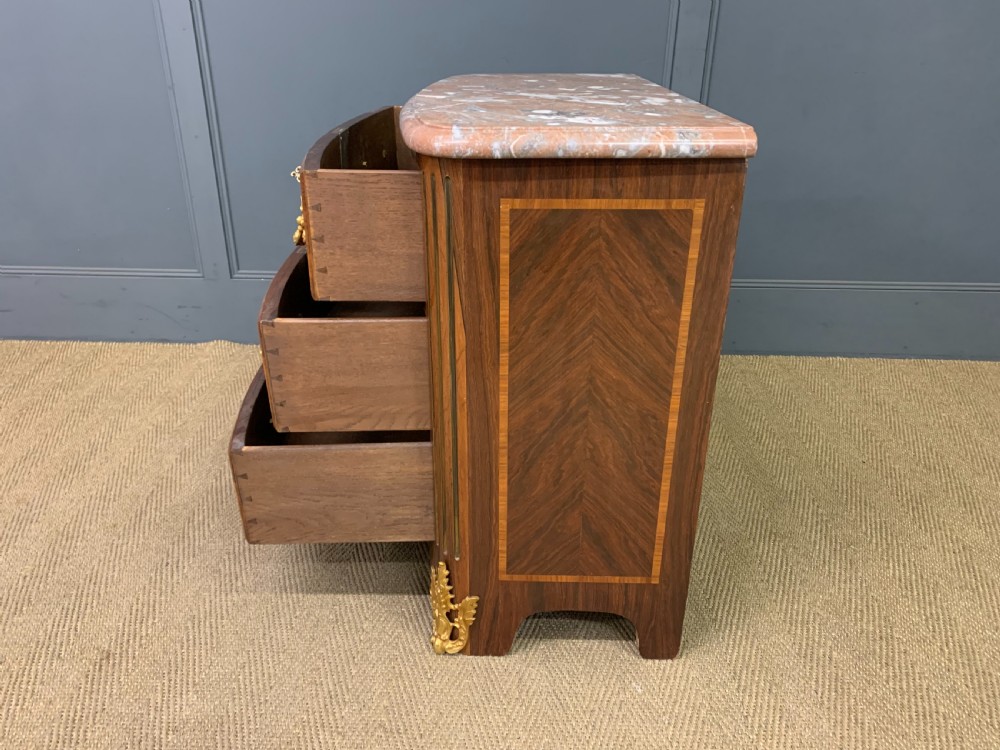 A French Louis XV style kingwood commode featuring three drawers, gilded metal mounts, and a variegated pink marble top. View XIII