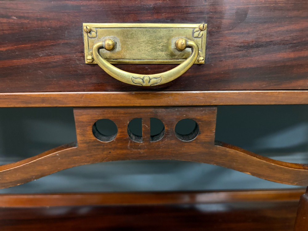 An Arts and Crafts mahogany display cabinet with stylized blue and green stained glass top panels, three glazed doors, and a blue fabric-lined interior. View IV