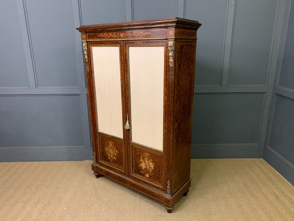 A 19th-century French double-door bookcase featuring amboyna and mahogany veneers, intricate floral marquetry, pleated cream fabric door panels, and brass mounts. View II