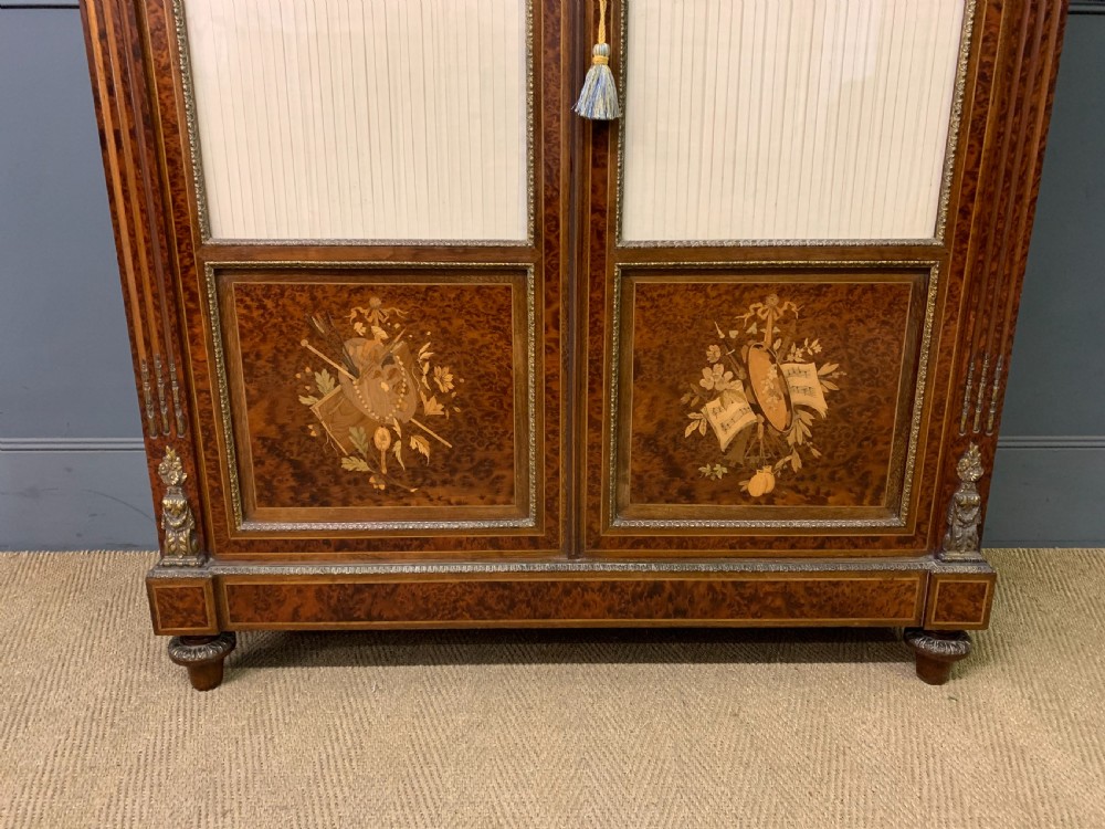 A 19th-century French double-door bookcase featuring amboyna and mahogany veneers, intricate floral marquetry, pleated cream fabric door panels, and brass mounts. View III